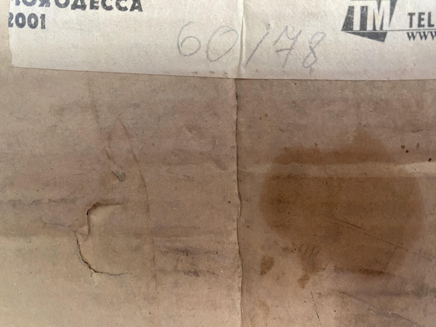 Worn beige cardboard box back with creases, stain, Prokopenko portrait