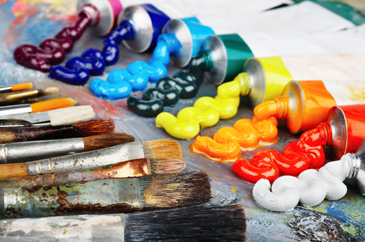 Colorful oil paint tubes with silver caps spilling glossy hues