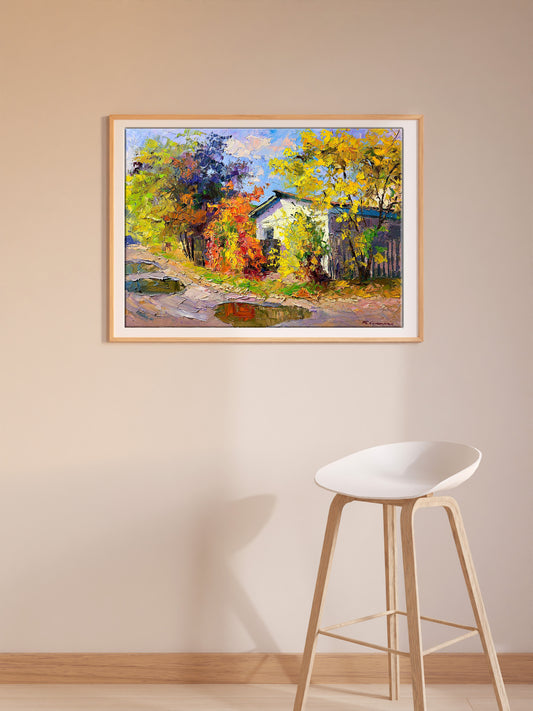 Vibrant autumn landscape painting of yellow-orange trees around white house in light wood frame
