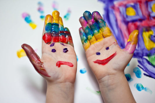 Vibrant multicolored hands painted as smiling and frowning faces for mindfulness