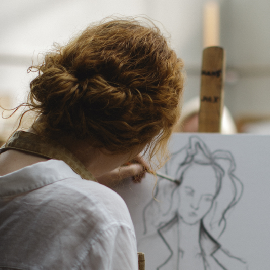 Back view of woman with curly auburn updo sketching canvas in painting genres article