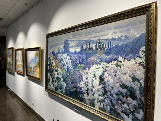 Ornate gold-framed oil painting of blossoming trees and spires