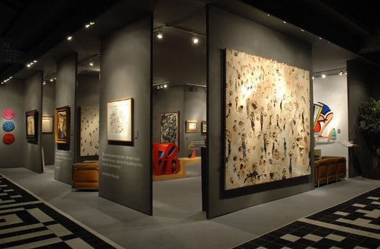 Large textured beige canvas with abstract black brown figures in gallery