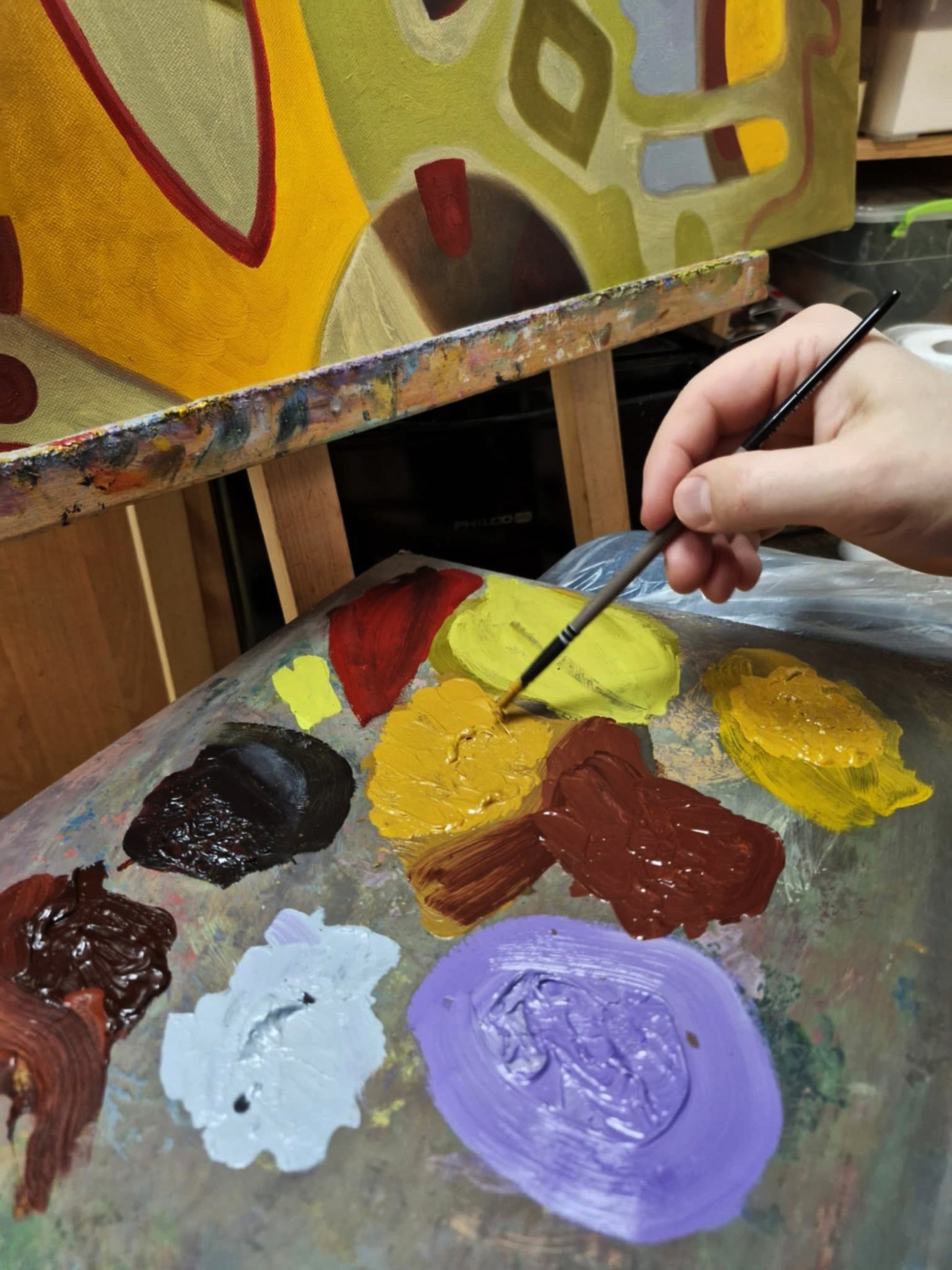 Hand with fine paintbrush over vibrant acrylic palette for Sergiy Voichenko oil painting