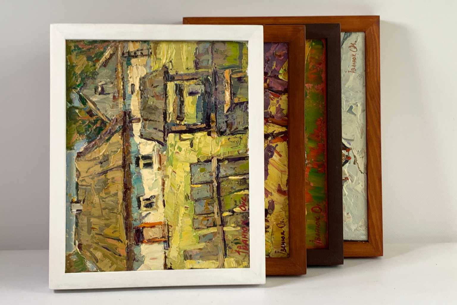 White-framed abstract painting with textured, impressionistic brushstrokes in yellow, green, and gray tones.