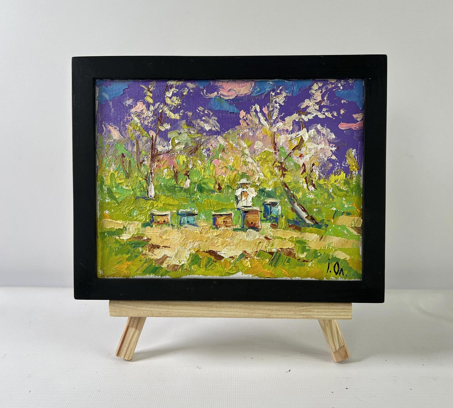 Oil painting Breath of Spring by Oleksiy Ivanyuk: bees, hives, purple sky, blossoms in black frame
