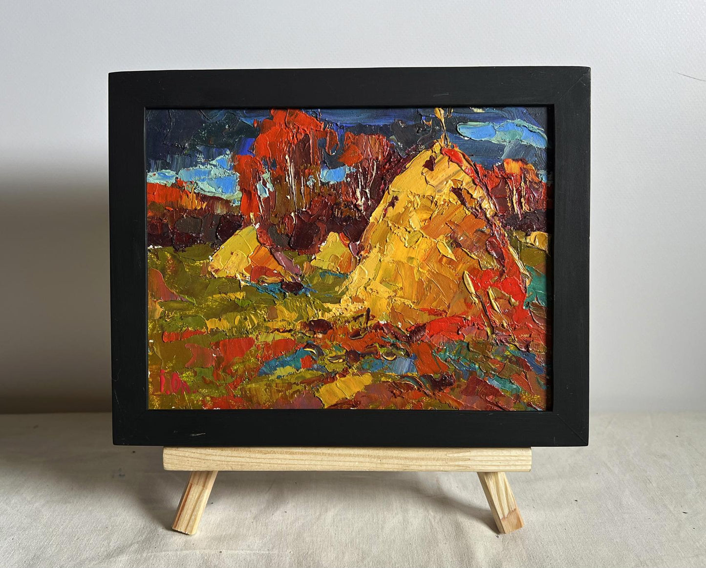 Oil painting of autumn fields and haystacks by Oleksiy Ivanyuk in black frame