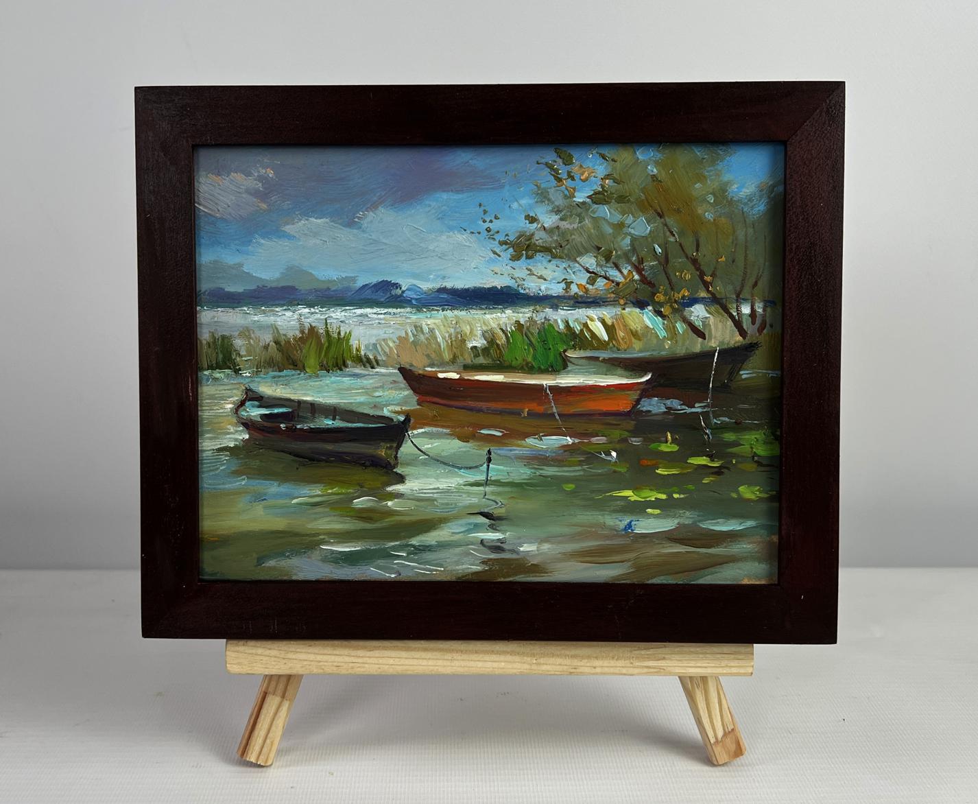 Oil painting of boats moored on shore by Yuriy Suprunchuk in dark frame