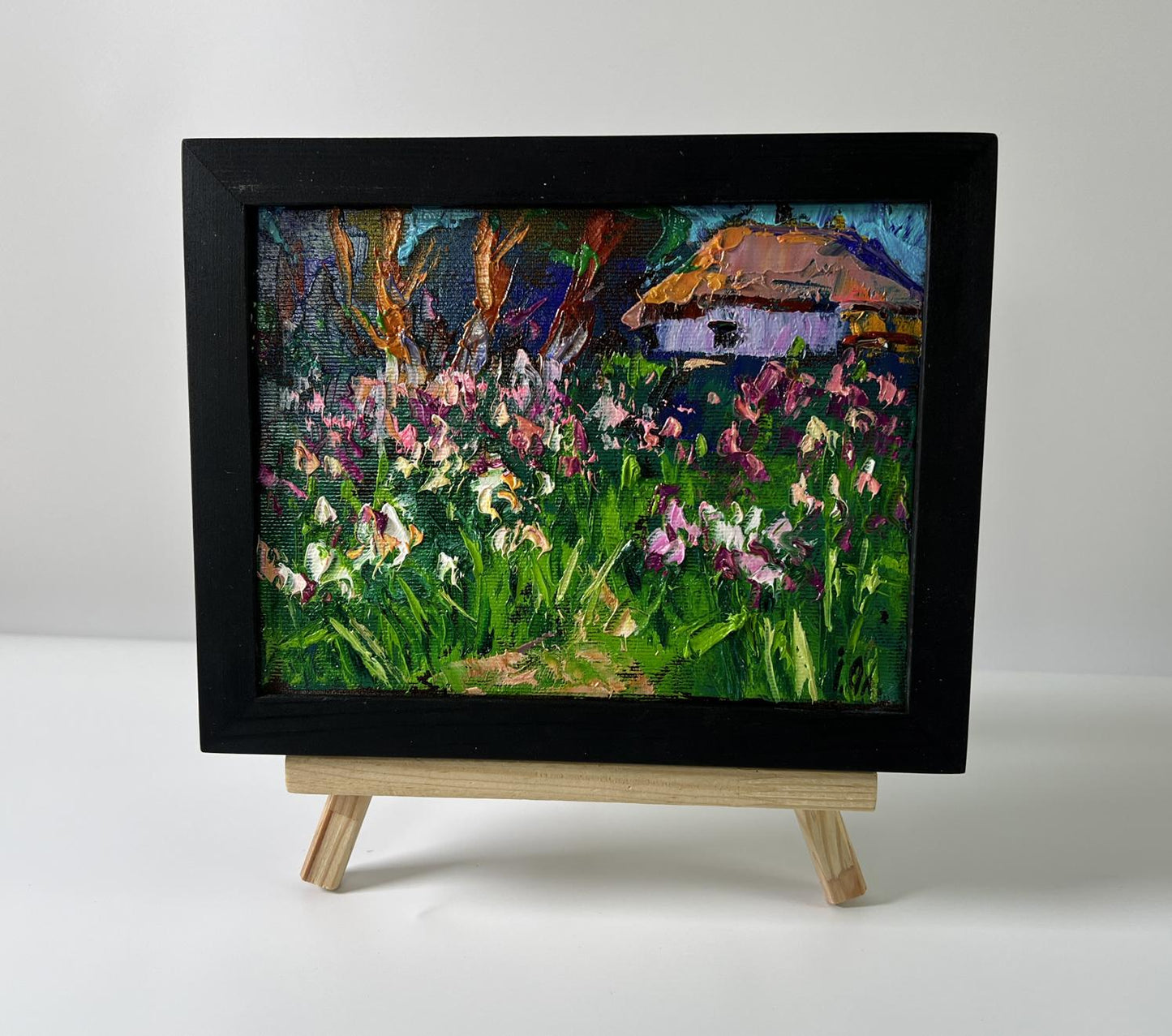 Oil painting by Oleksiy Ivanyuk: irises field with thatched cottage on easel