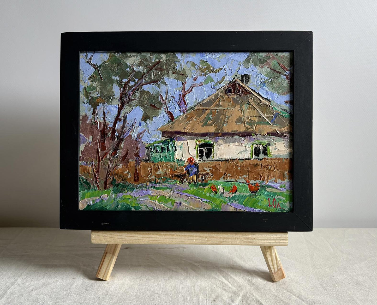 Framed impressionistic oil painting of rustic cottage with grandma on bench by Oleksiy Ivanyuk
