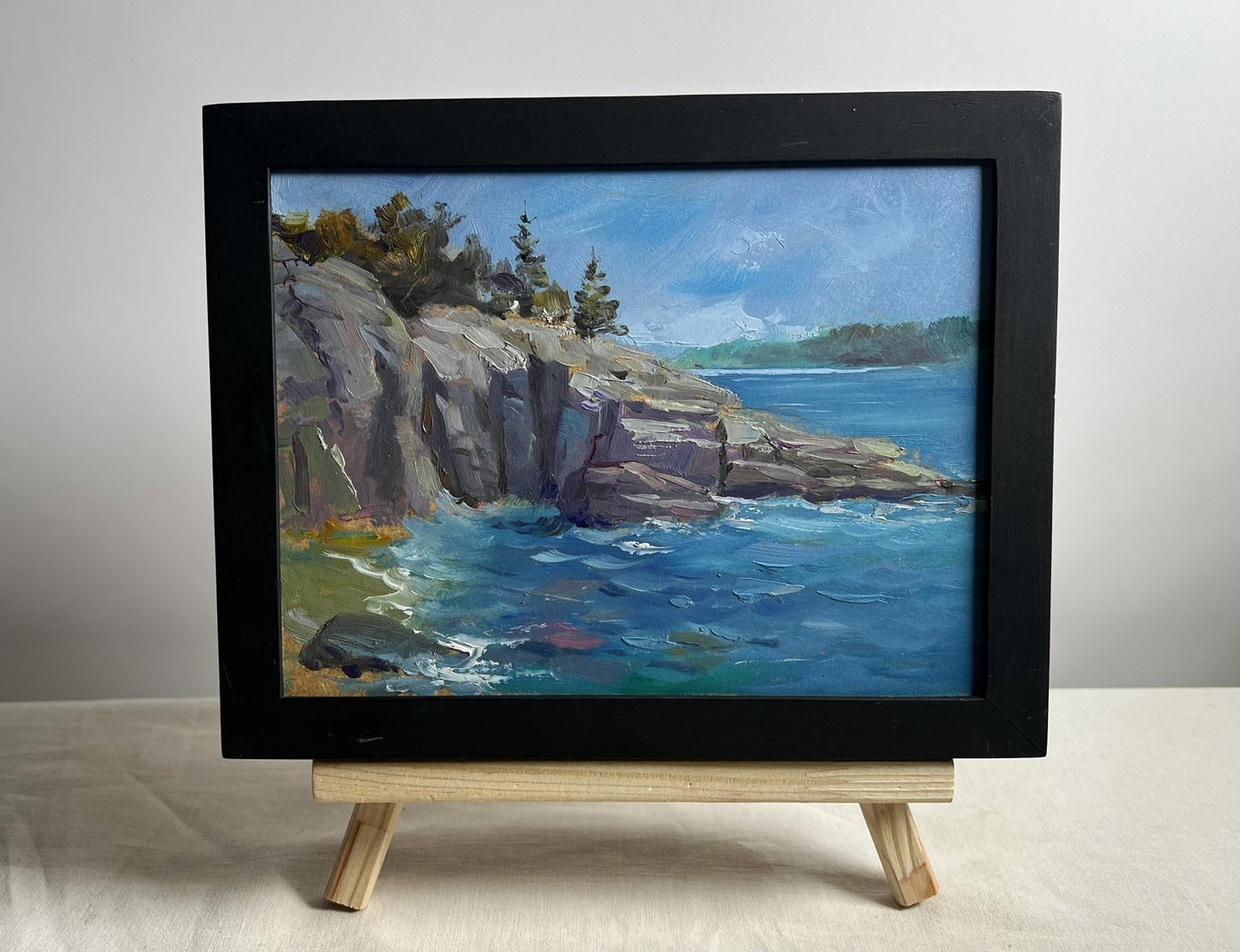 Black-framed oil painting Cloudy day at sea by Yuriy Suprunchuk on wooden easel