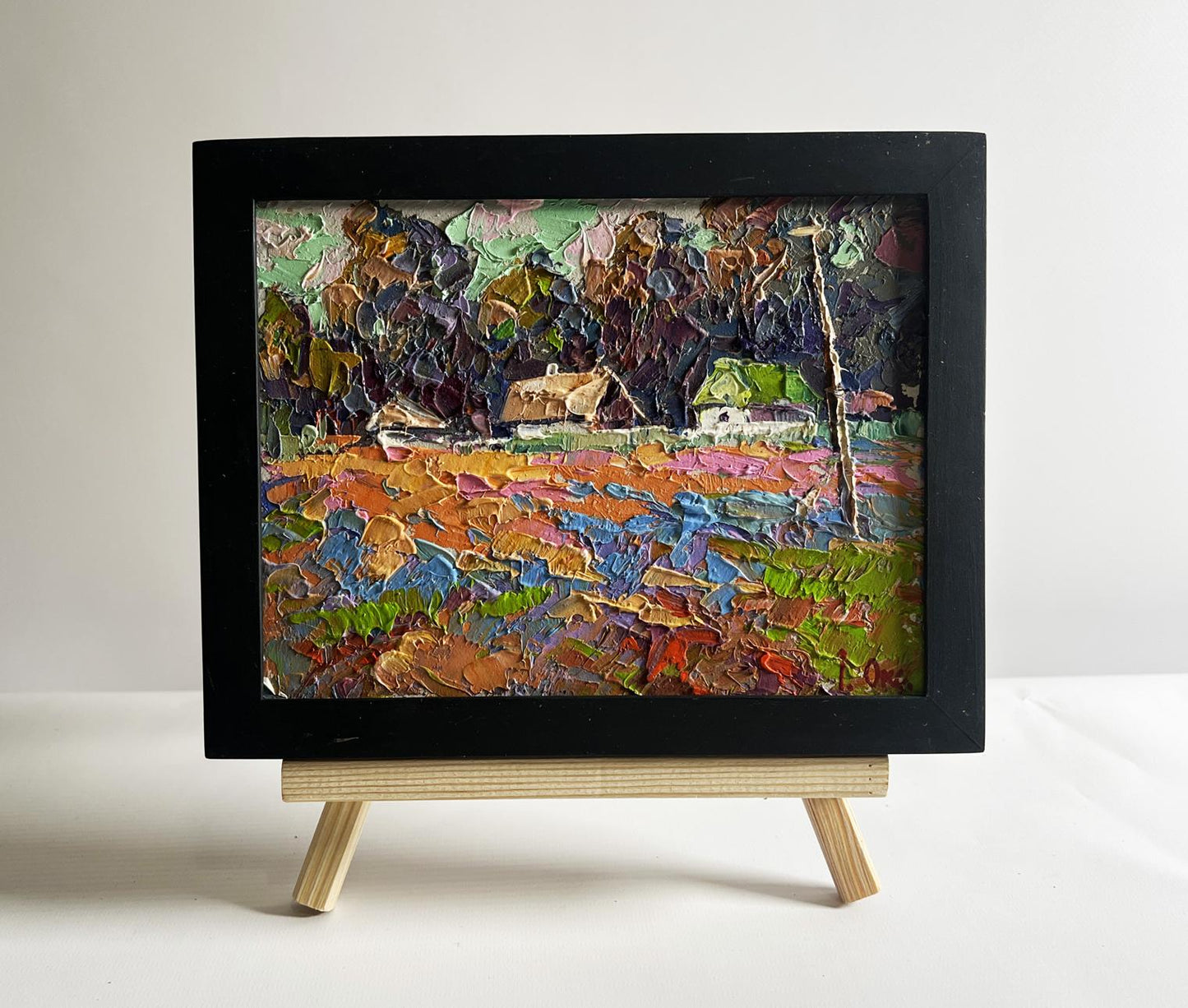 Vibrant impressionist oil painting of colourful fields and village by Oksana Ivanyuk in black frame