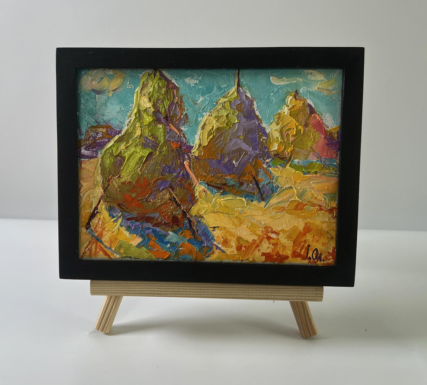 Oil painting of colorful haystacks in field by Oleksiy Ivanyuk in black frame
