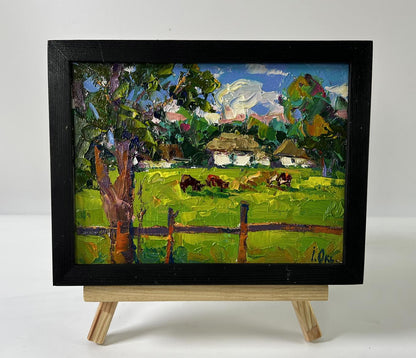 Oil painting by Oksana Ivanyuk: cows grazing in lush green meadow, framed