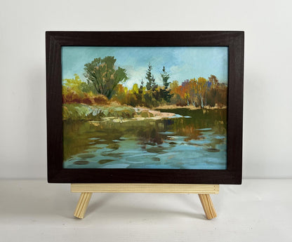 Oil painting by Yuriy Suprunchuk: serene autumn river with vibrant trees reflected in calm blue water