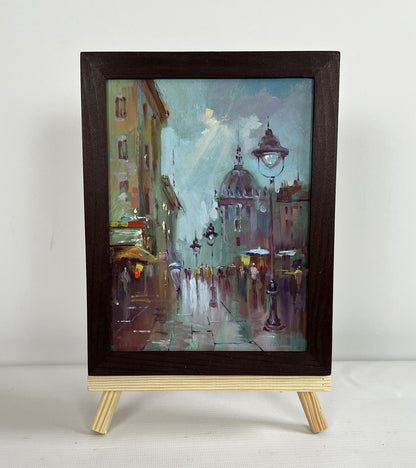 Framed oil painting of rainy city street hustle by Yuriy Suprunchuk
