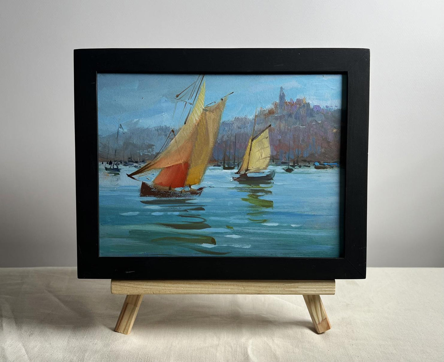 Framed oil painting of sailboats by Yuriy Suprunchuk on wooden easel
