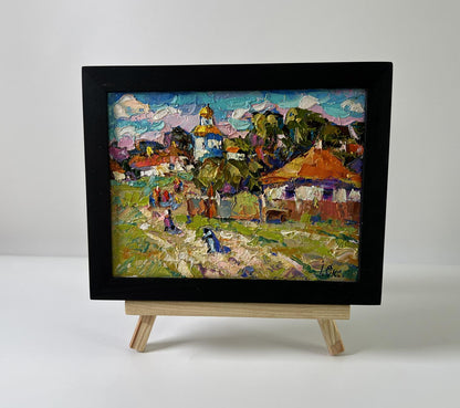 Vibrant impressionist oil painting of village festive day by Oksana Ivanyuk in black frame