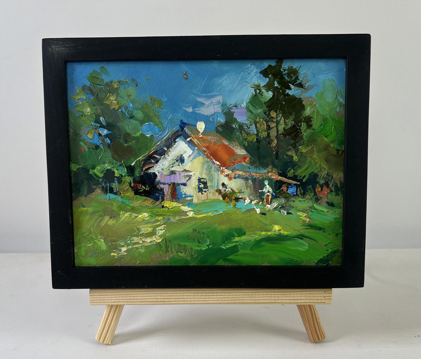 Oil painting Quiet village life by Yuriy Suprunchuk in black frame on easel