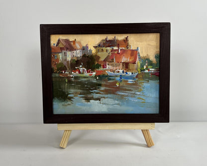 Framed oil painting of sunset glow over harbor rooftops by Yuriy Suprunchuk