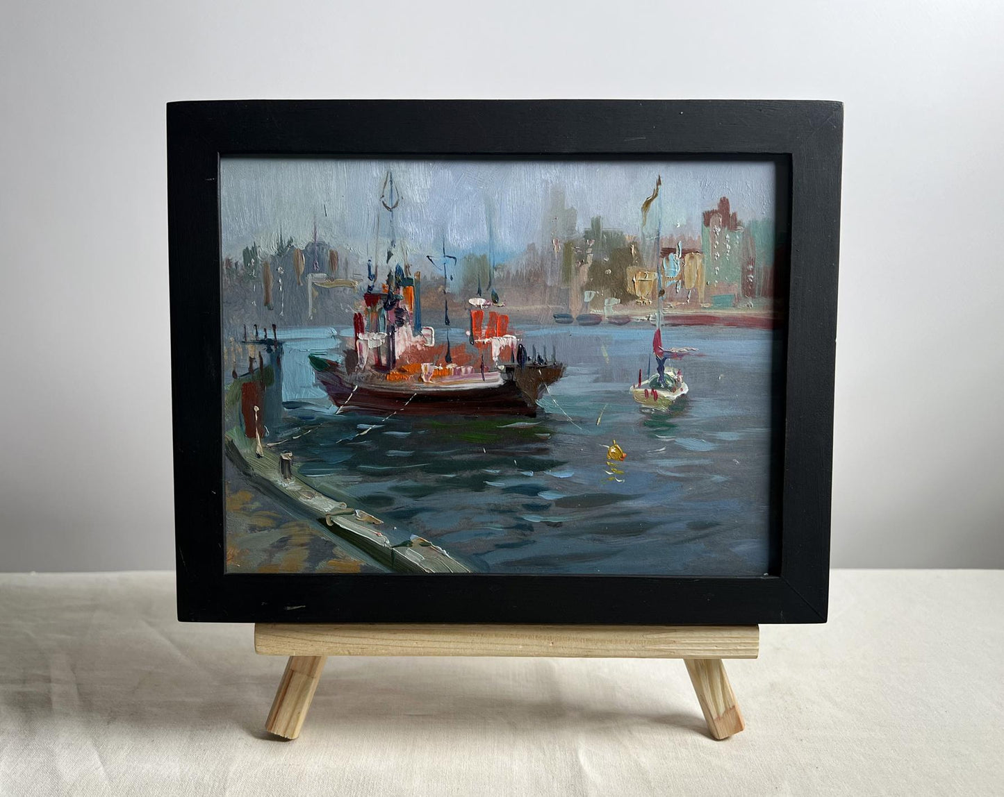 Black-framed oil painting of ship at pier by Yuriy Suprunchuk