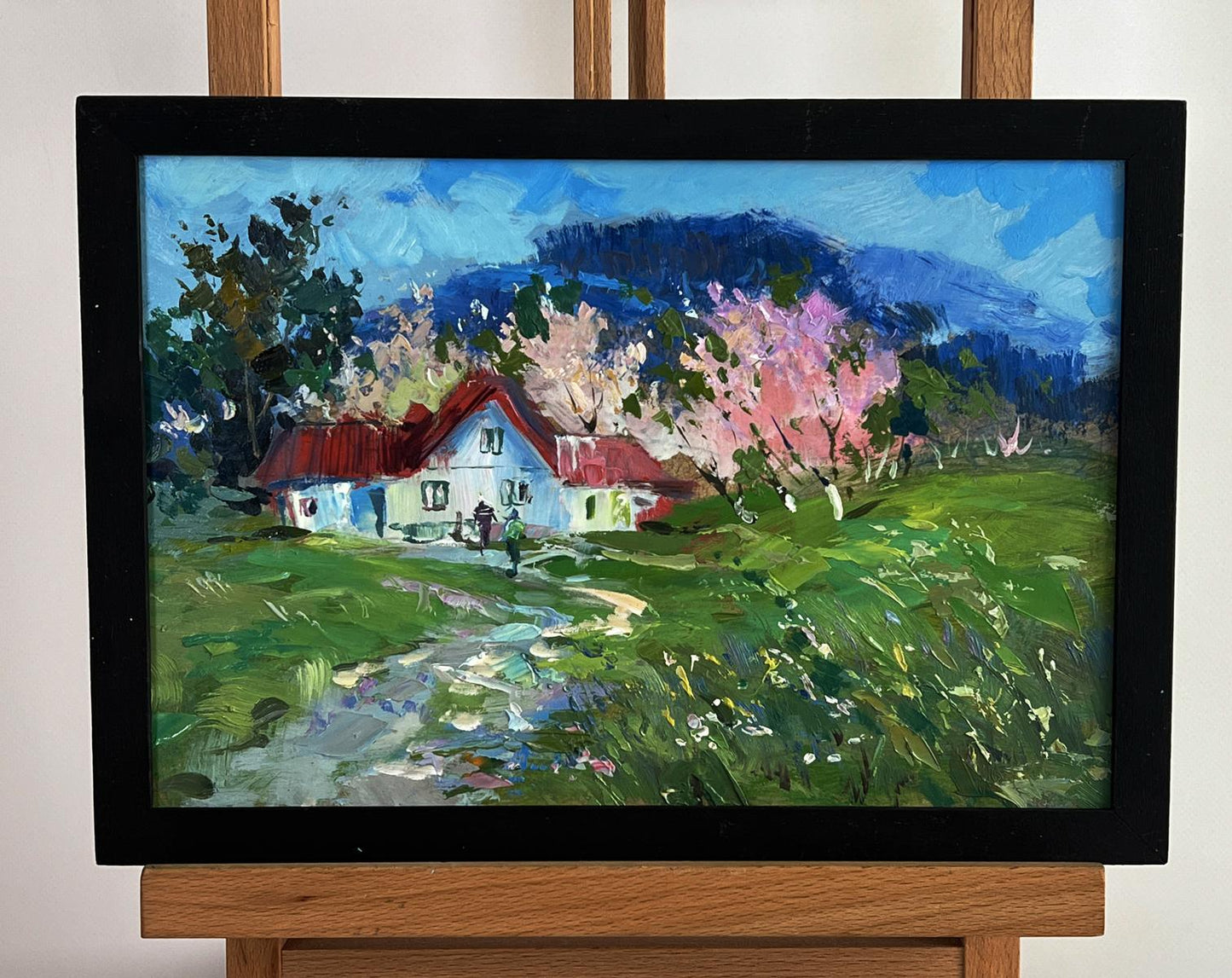Oil painting of rustic white house with red roof among blooming cherry trees by Yuriy Suprunchuk