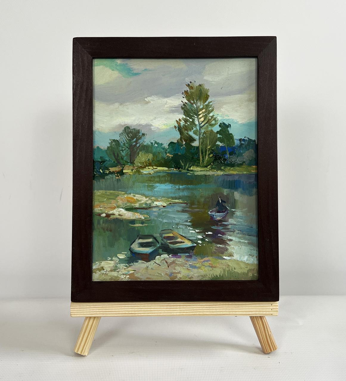 Dark wood-framed oil painting of river in forest thicket by Yuriy Suprunchuk on easel