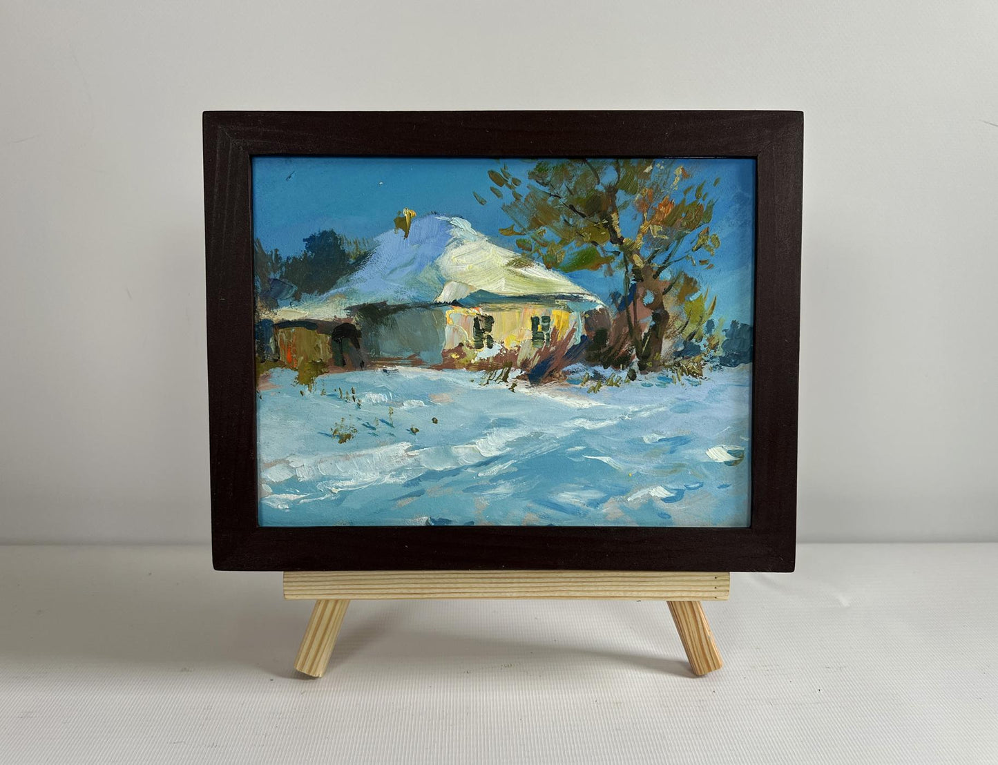 Framed oil painting of snowy rural scene with yellow house by Yuriy Suprunchuk