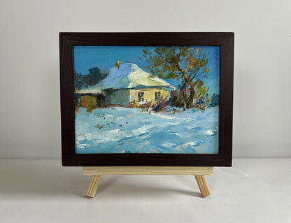Framed oil painting of snowy rural scene with yellow house by Yuriy Suprunchuk