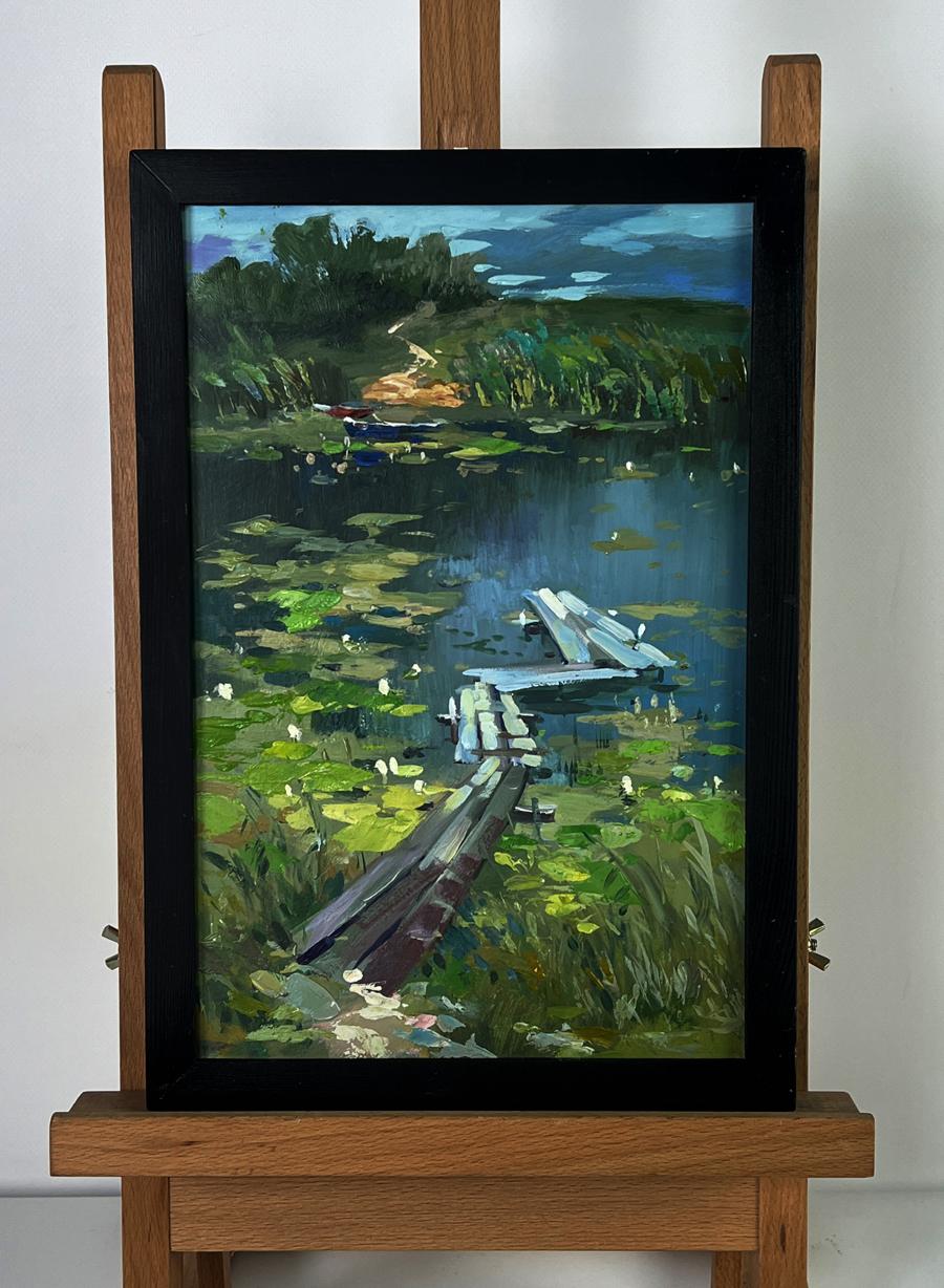 Framed oil painting of serene lakeside with boats on river bank by Yuriy Suprunchuk