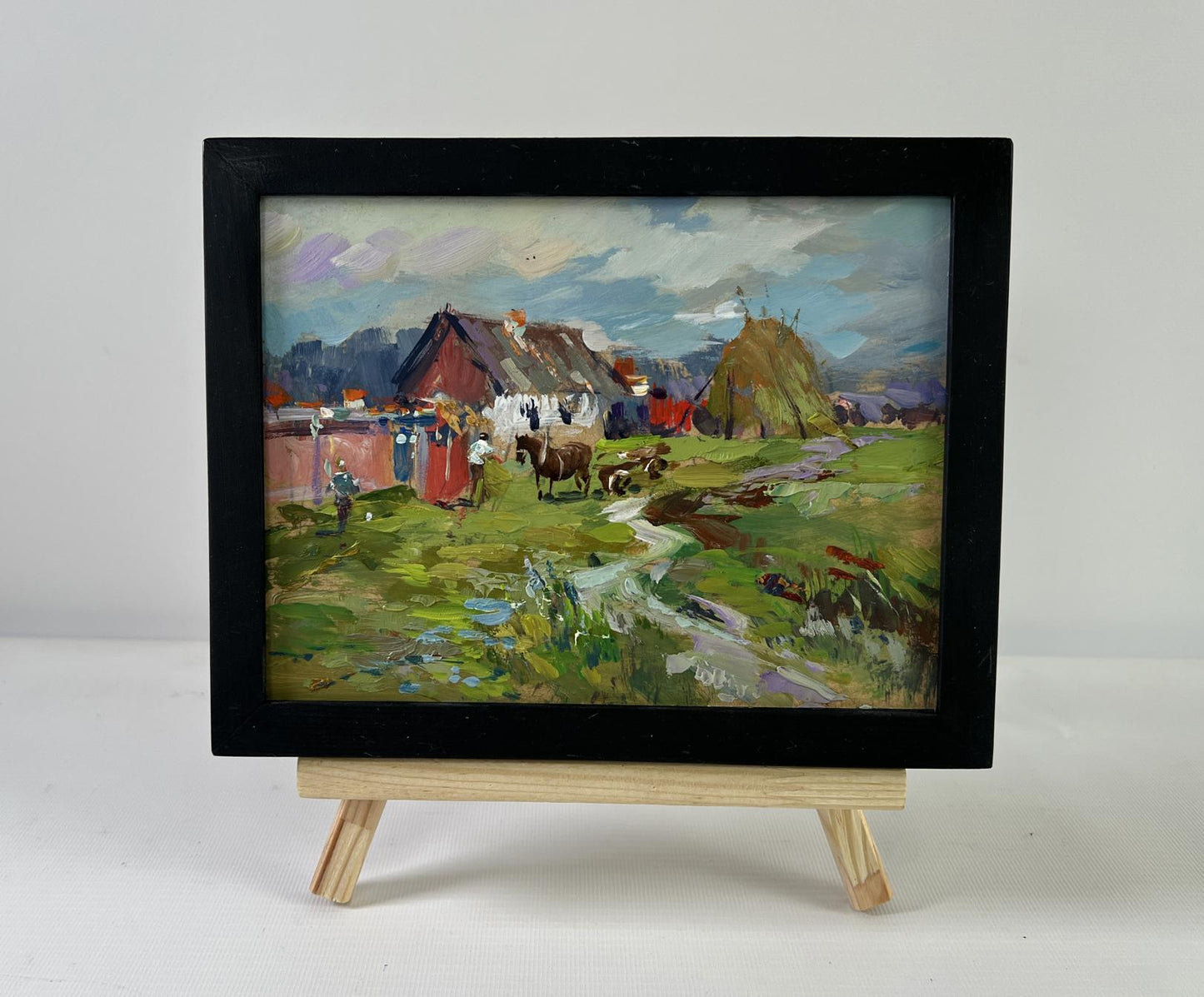 Framed impressionistic oil painting of horses by hay in rustic village by Yuriy Suprunchuk