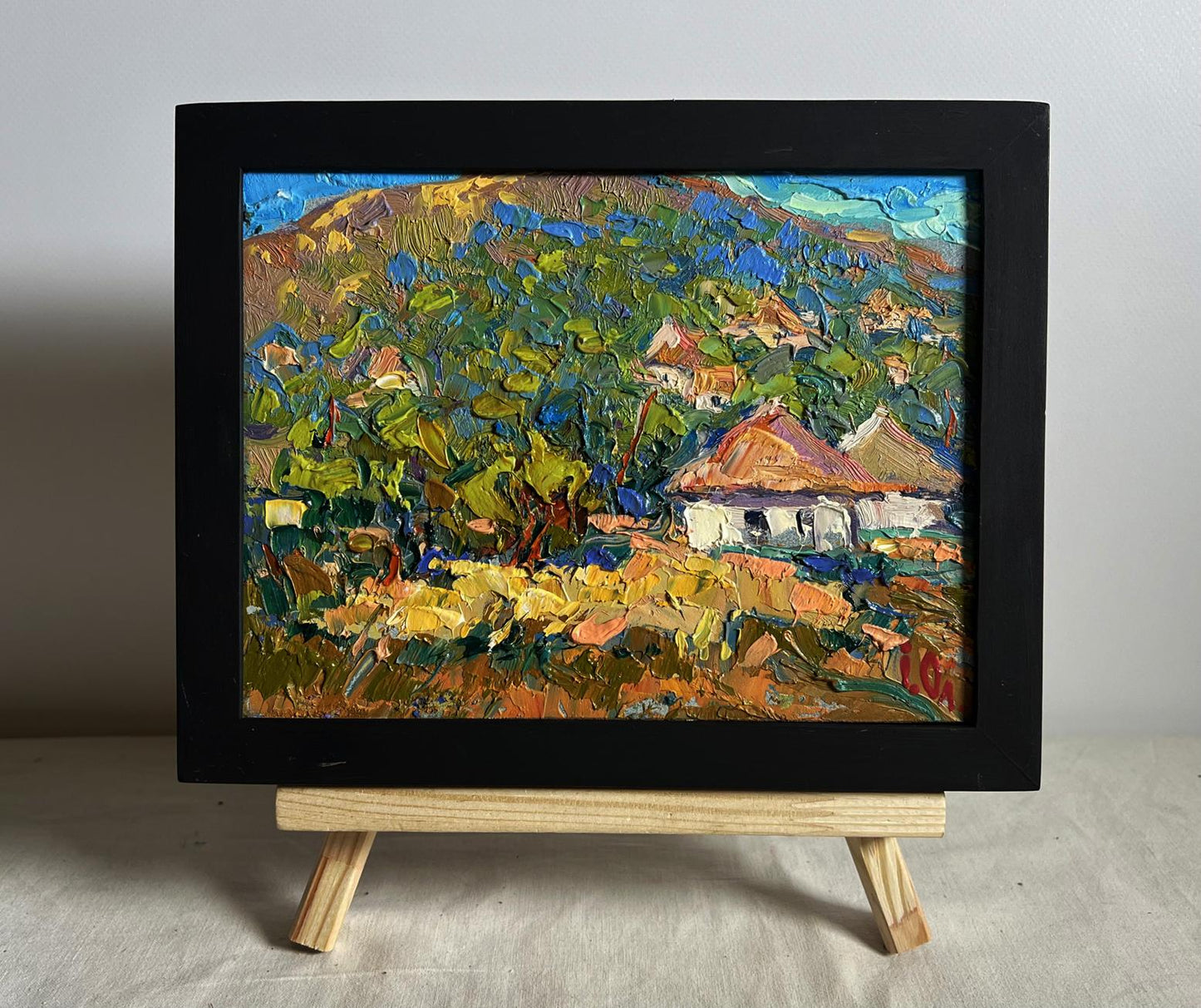 Vibrant Oleksiy Ivanyuk oil painting of village under mountain on black frame easel