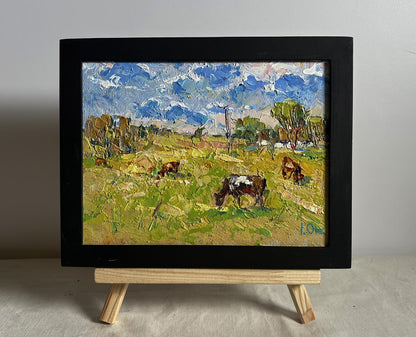 Oil painting of cows grazing on hot day in field by Oksana Ivanyuk, framed