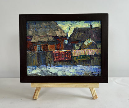 Oil painting of sunset behind rustic snow village rooftops by Oksana Ivanyuk