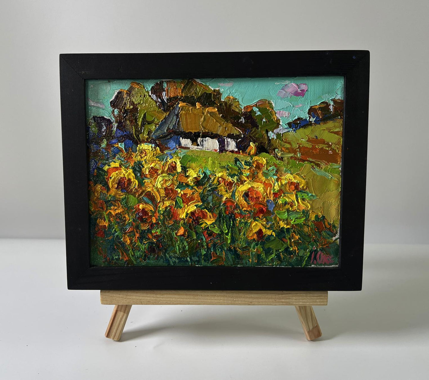 Oil painting of rural sunflowers by Oksana Ivanyuk in black frame on easel