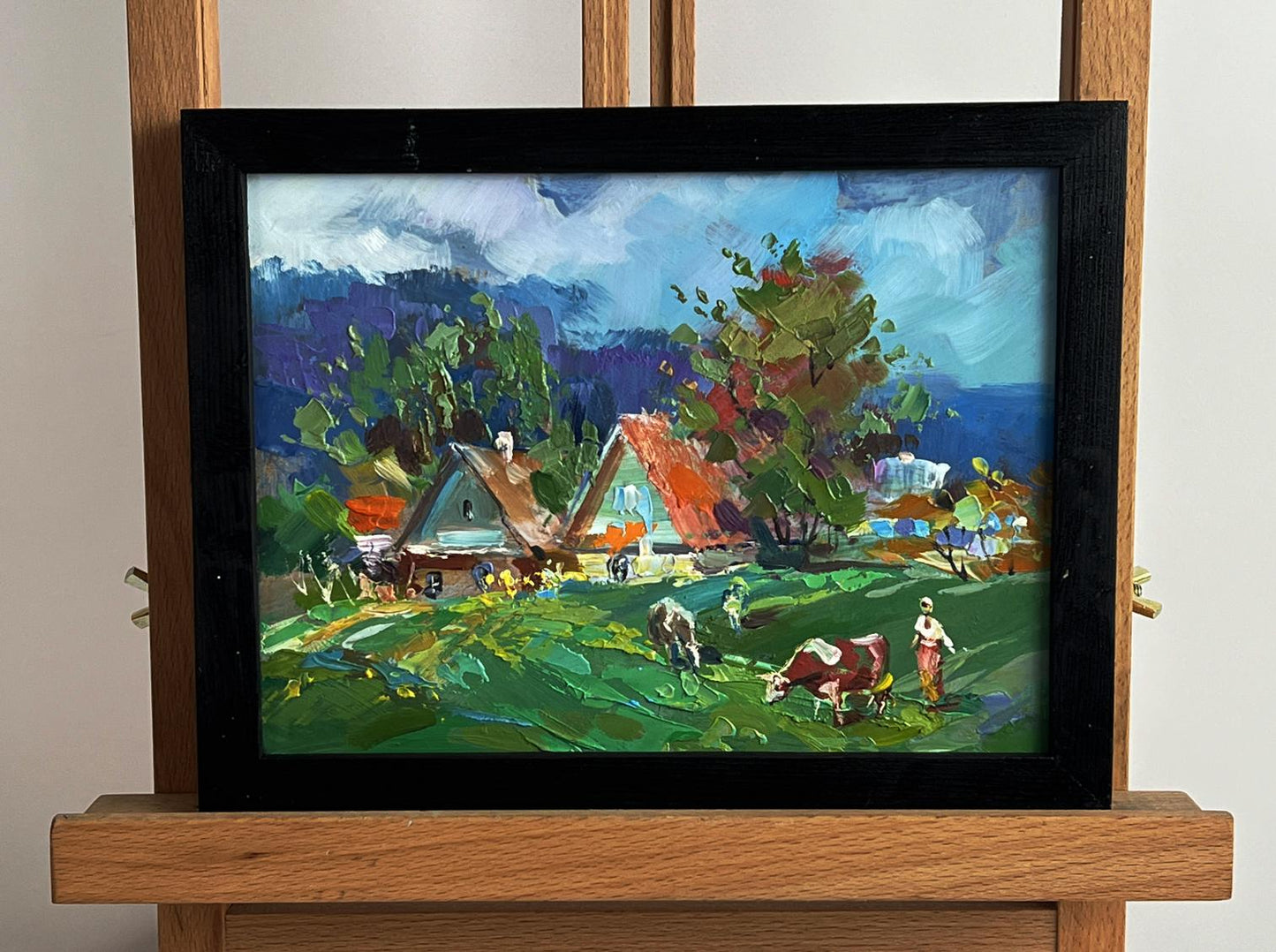 Vibrant impressionist oil painting by Yuriy Suprunchuk of cows grazing in village, framed in black