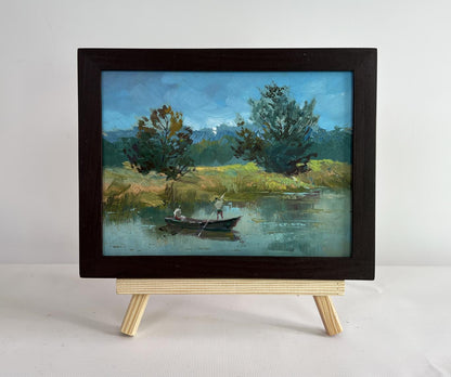 Oil painting by Yuriy Suprunchuk: two people sailing on serene river in boat, framed on easel
