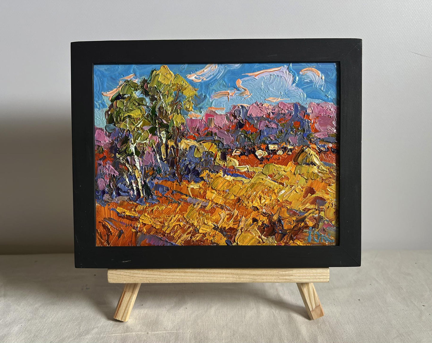 Oil painting Golden autumn field by Oksana Ivanyuk in black frame on easel