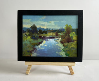 Black-framed oil painting of sunset clouds over serene river by Yuriy Suprunchuk