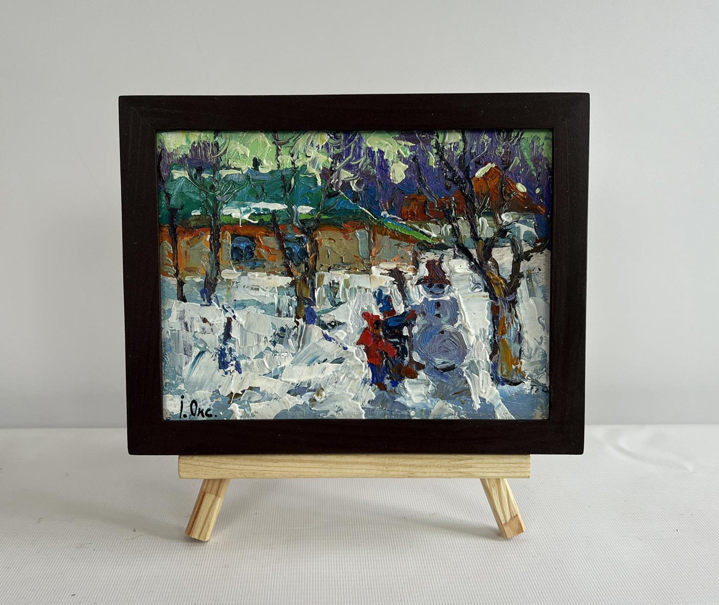 Framed oil painting by Oksana Ivanyuk of children making snowman in snow