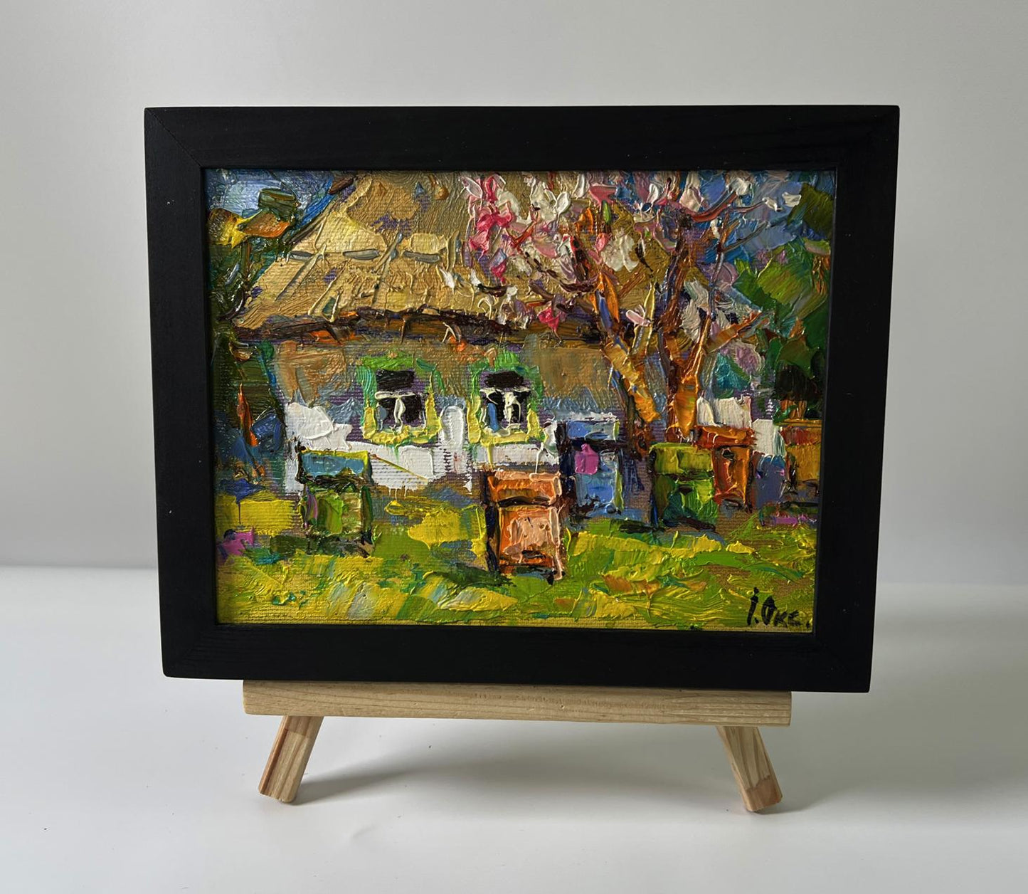 Oil painting House in the village by Oksana Ivanyuk in black frame on easel