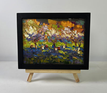 Vibrant oil painting of blossoming orchard by Oksana Ivanyuk in black frame