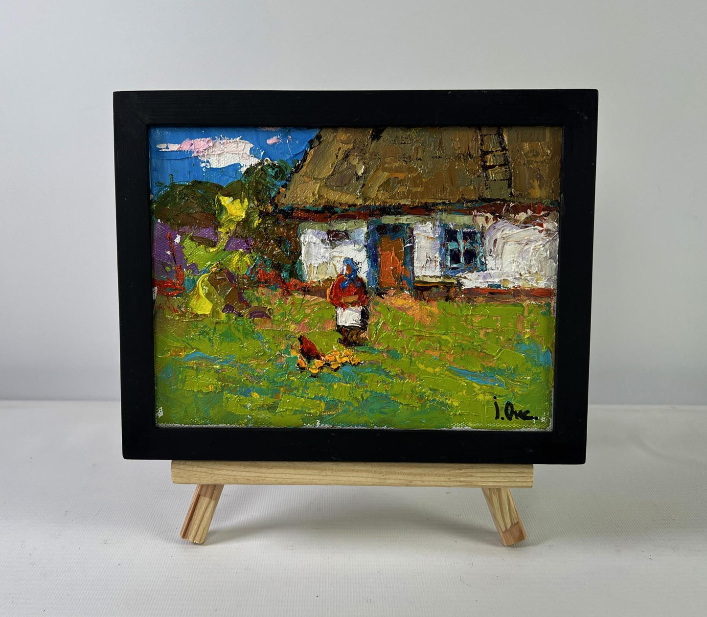 Vibrant impressionist oil painting by Oksana Ivanyuk of rustic village with thatched house in black frame