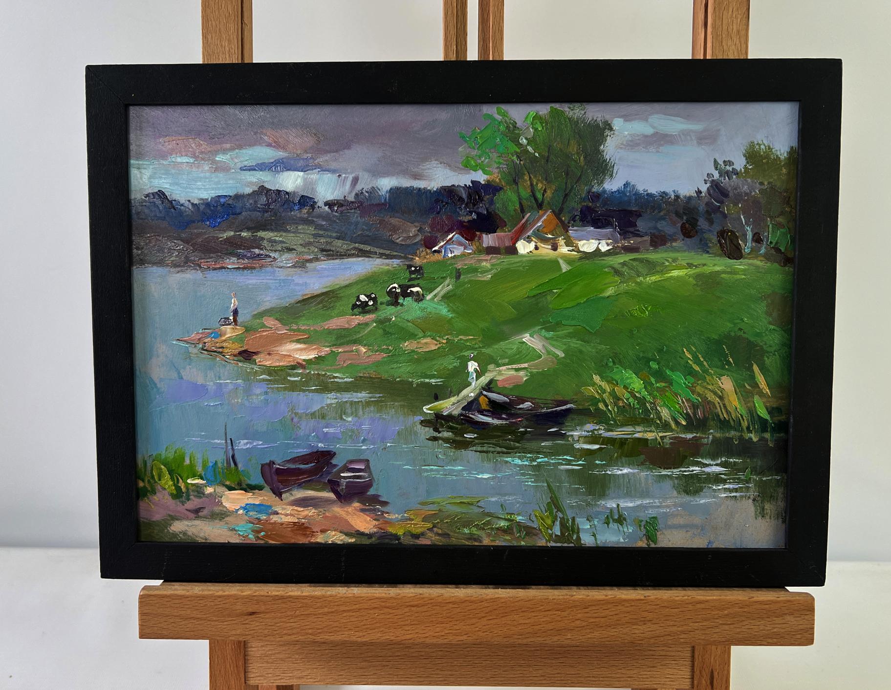 Black-framed oil painting of Yuriy Suprunchuk lakeside village with hills, boats