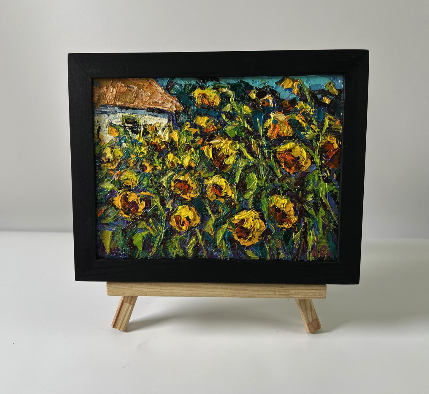 Oil painting of field sunflowers by Oleksiy Ivanyuk in black frame on easel