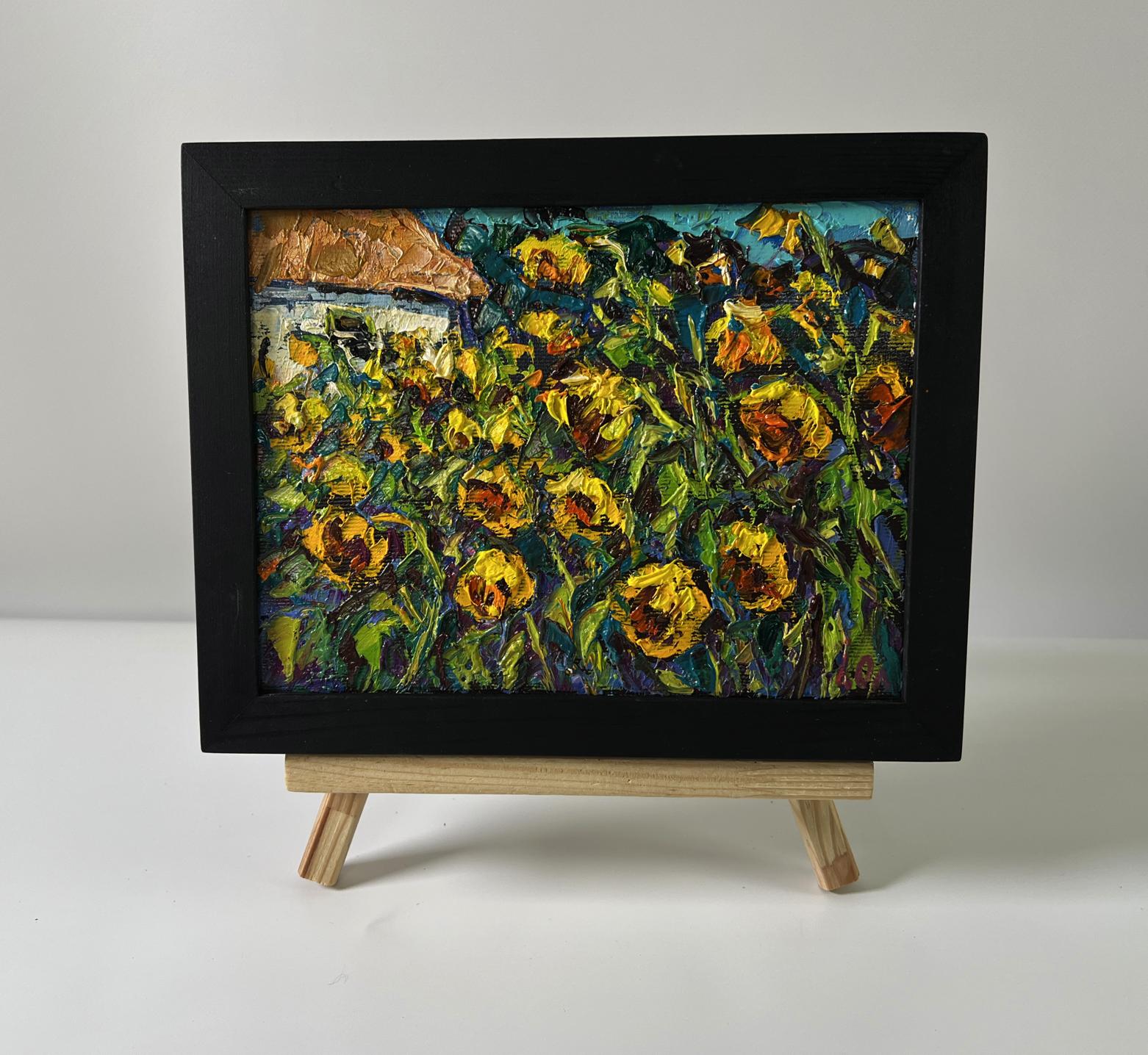 Oil painting of field sunflowers by Oleksiy Ivanyuk in black frame on easel