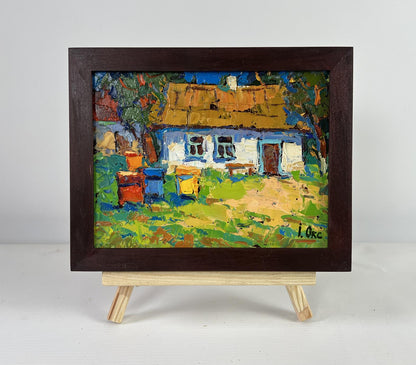 Oil painting of rustic cottage with beehives by Oksana Ivanyuk