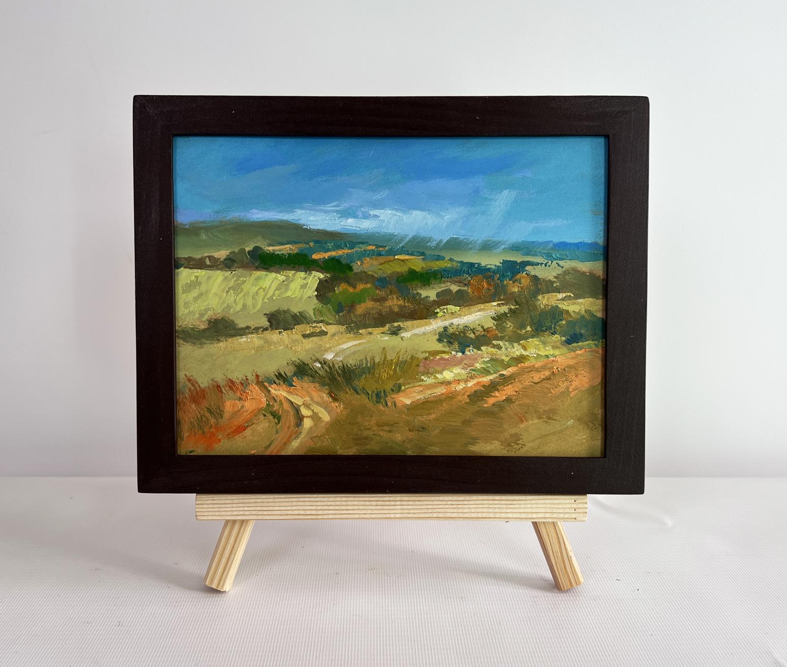 Oil painting of green fields and hills by Yuriy Suprunchuk in black frame