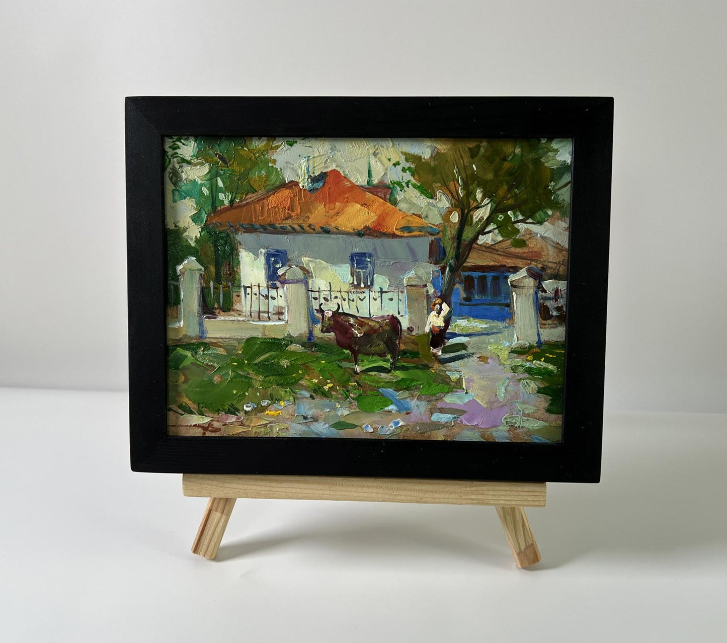 Oil painting by Yuriy Suprunchuk: cow near orange-roofed rustic house