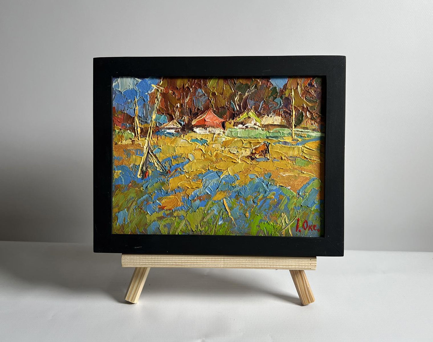 Oil painting by Oksana Ivanyuk: vibrant cow in field near village, framed